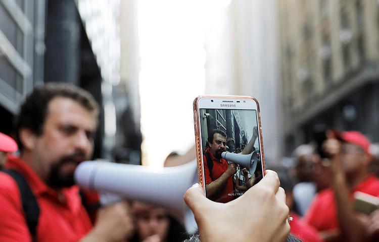A cell phone is used to film a homelessness protest in Sao Paulo in December 2017. Ahead of October elections, police are tasked with combating the spread of fake news. (Reuters/Nacho Doce)