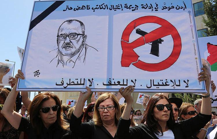 Relatives of Nahed Hattar carry signs condemning his murder during a protest in Amman in September 2016. The Jordanian commentator and writer was shot dead outside a court while on trial for blasphemy over a Facebook cartoon. (AP/Raad Adayleh)