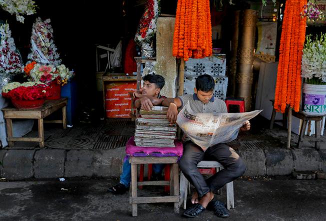 A man reads a newspaper outside a Dhaka flower stall in 2015. Bangladesh's press say a climate of fear amid legal action, attacks, and threats makes covering sensitive issues difficult. (AP)