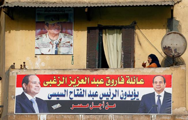 In Cairo, Egypt, a woman sips on a cup of tea as she sits behind a poster of Egypt's President Abdel Fattah al-Sisi, who will run for a second term in an upcoming election. The poster reads "We've chosen you for a second term". (Reuters/Mohamed Abd El Ghany)