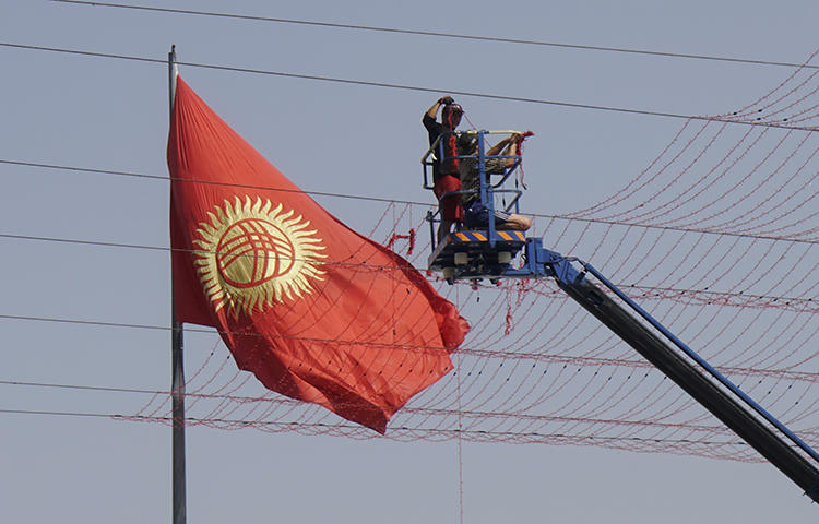 Workers set up street decorations in front of the national flag in Bishkek, Kyrgyzstan in September 2017. Kyrgyz authorities charged freelance journalist Elnura Alkanova with seeking and disclosing confidential commercial information following the publication last fall of investigative reports on the allegedly corrupt sale of government property near the capital Bishkek, the independent online news site 24.kg reported. (Reuters/Shamil Zhumatov)