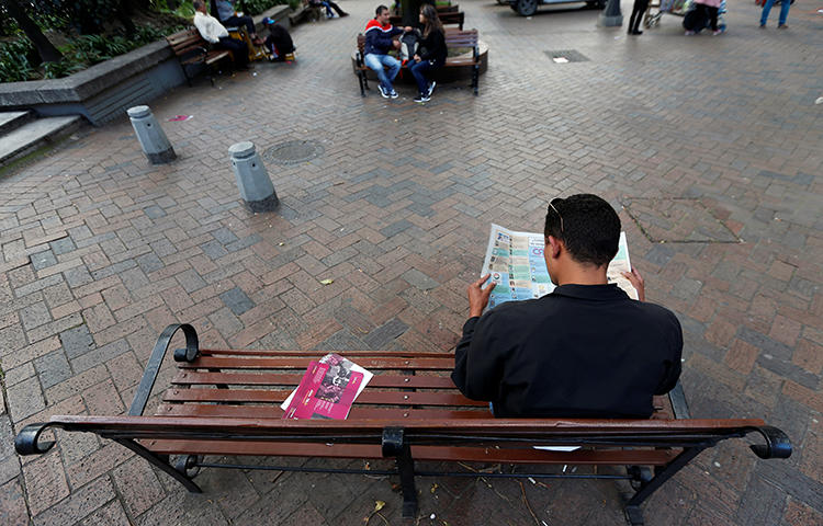 A man reads a newspaper in a park in Bogota, Colombia in January 2018. A Colombian court on February 1 sentenced the gunman responsible for the 2015 murder of Colombian radio journalist Luis Antonio Peralta Cuéllar and his wife Sofía Quintero. (Reuters/Jaime Saldarriaga)