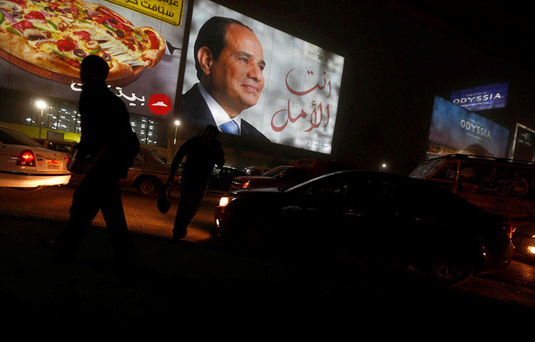 People walk near a billboard showing a picture of Egyptian President Abdel Fattah al-Sisi during the presidential election in Cairo, Egypt, March 28, 2018. During the election, Egyptian authorities blocked news sites and threatened journalists with retaliatory measures, according to reports. (Reuters/Amr Abdallah Dalsh)