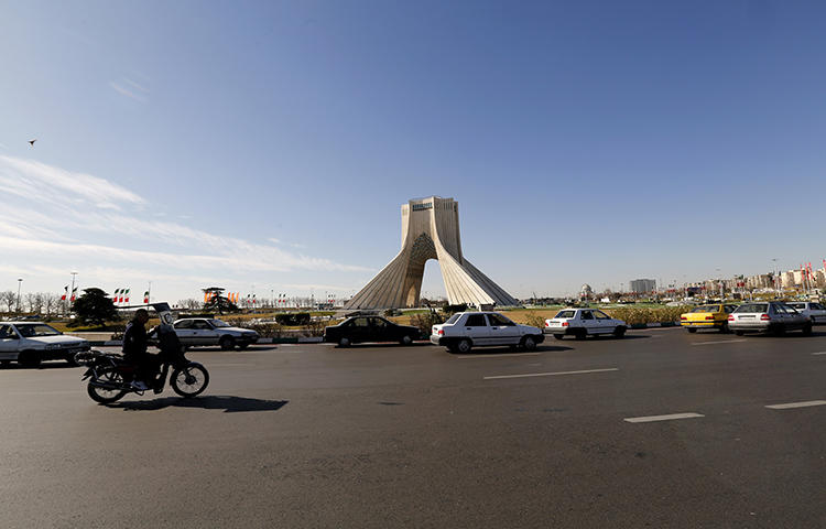 Iranian motorists drive past the Azadi Tower in the capital Tehran in January 2018. Iranian security forces on February 19 arrested Reza Entessari and Kasra Nouri, reporters with the Sufi news website Majzooban-e-Noor, while they were covering the violent dispersal of religious protests in Tehran, according to news reports. (AFP/Atta Kenare)