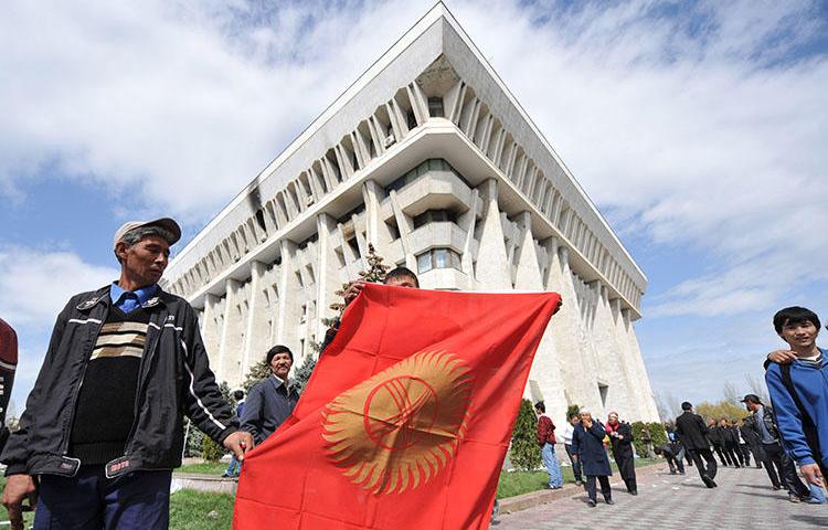 A man holds the Kyrgyz flag in front of the government building in Bishkek in April 2010. CPJ has joined calls for the Kyrgyz authorities to end the repressive climate for the country's press. (AFP/Vyacheslav Oseledko)