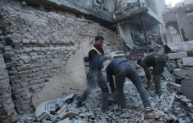 Members of the Syrian civil defense forces known as White Helmets search for victims following an airstrike in Arbin, eastern Ghouta on February 9, 2018. An airstrike on March 12 killed Arbin Unified Media Office photographer Bashar al-Attar. (AFP/Abdulmonam Eassa)
