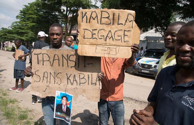 Opposition supporters hold placards reading 'Kabila - get lost' and 'Transition without Kabila' during a protest in Kinshasa on November 30, 2017. At least six local journalists were detained while trying to cover protests across the DRC. (AFP/Junior Kannah)