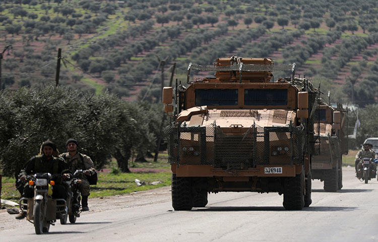 Turkish-backed Free Syrian Army members ride on a motorbike near a Turkish military vehicle in Afrin, Syria on March 19, 2018. Turkish forces and FSA factions seized Afrin from the Kurdish People's Protection Union (YPG) on March 18 after a two-month offensive, news reports stated. (Reuters/Khalil Ashawi)