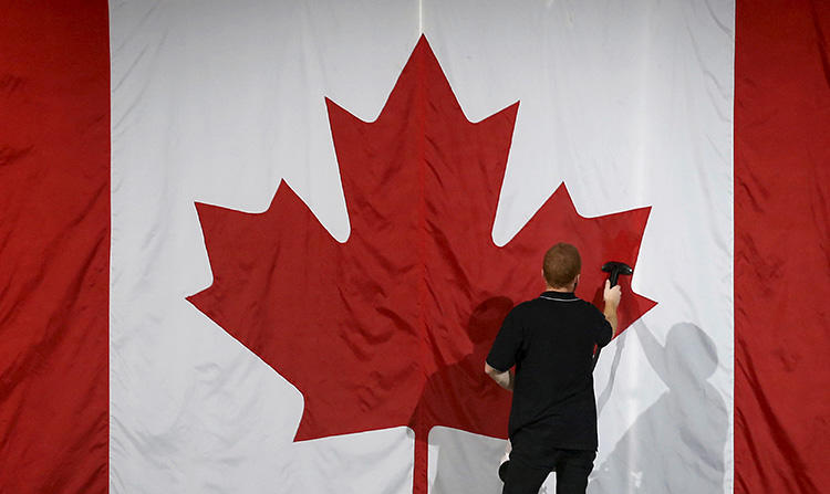 Um trabalhador limpa a vapor uma bandeira canadense em Montreal, Quebec, em 2015. A Rádio Canadá está apelando da decisão da Suprema Corte de Quebec ordenando que a repórter Marie-Maude Denis revele suas fontes. (Reuters / Jim Young)