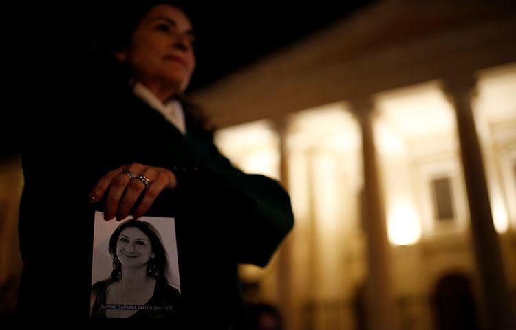 A woman holds a photo of Daphne Caruana Galizia at a memorial for the murdered journalist outside the Courts of Justice in Valletta, Malta, in February 2018. Three people are on trial in connection to her murder. (Reuters/Darrin Zammit Lupi)