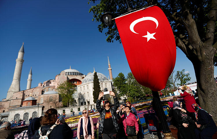People take pictures in Istanbul with the Hagia Sophia in the background on April 21, 2018. An Istanbul court convicted 14 people affiliated with the daily Cumhuriyet on terrorism-related charges, the newspaper reported. (Reuters/Murad Sezer)