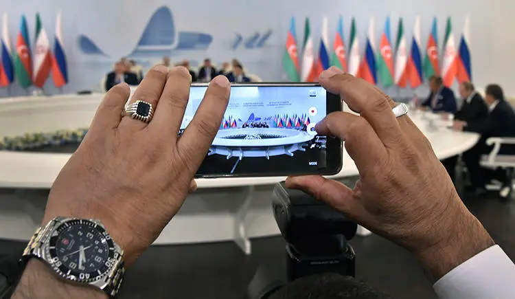 A cell phone takes photos of an August 2016 meeting in Baku between the presidents of Russia, Iran, and Azerbaijan. President Ilham Aliyev claims internet is 'free of censorship' in Azerbaijan, but authorities have blocked access to critical news websites. (Alexander Nemenov/Pool/AP)