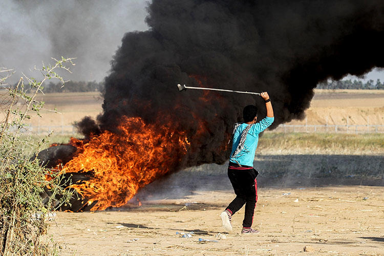 A Palestinian youth swings a sling shot during clashes after a demonstration near the border with Israel, east of Khan Younis in the Gaza Strip on April 1, 2018. (AFP/Said Khatib)
