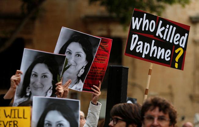 People hold up photos of anti-corruption journalist Daphne Caruana Galizia during a vigil on April 16, 2018, marking the sixth month anniversary of her assassination in Malta. The Council of Europe appointed Pieter Omtzigt as a special rapporteur to monitor the ongoing investigation into her murder, according to reports. (Reuters/Darrin Zammit Lupi)
