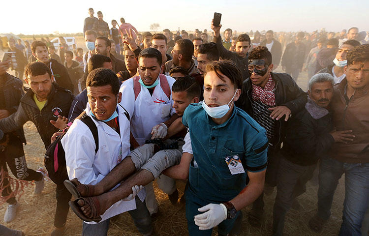 A wounded Palestinian demonstrator is evacuated during clashes with Israeli troops at the Israel-Gaza border at a protest demanding the right to return to their homeland, in the southern Gaza Strip on April 9, 2018. Photojournalist Yaser Murtaja was injured when a live round hit him in the abdomen while he was covering protests in the area east of Khan Younis city and died the next day from injuries, according to reports. (Reuters/Ibraheem Abu Mustafa)
