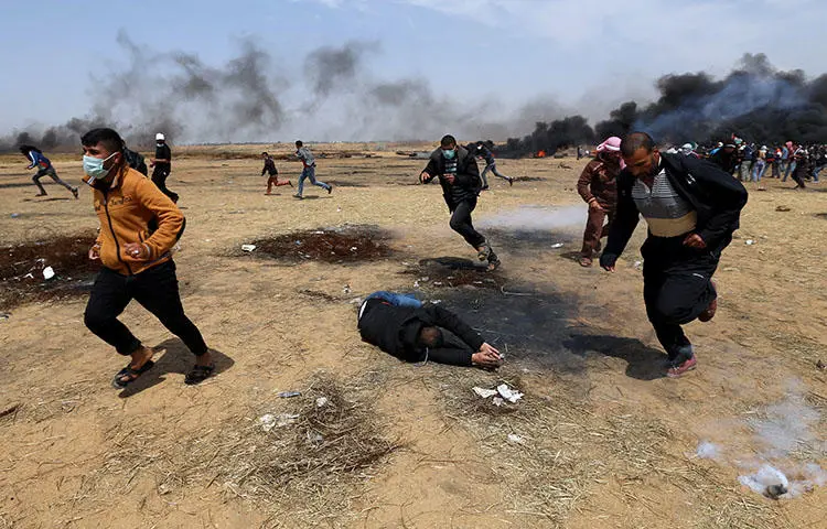 A wounded Palestinian falls to the ground during clashes with Israeli troops at a protest in the southern Gaza Strip on April 27, 2018. At least seven journalists were injured on April 27 while covering the protests, according to CPJ research. (Reuters/Ibraheem Abu Mustafa)