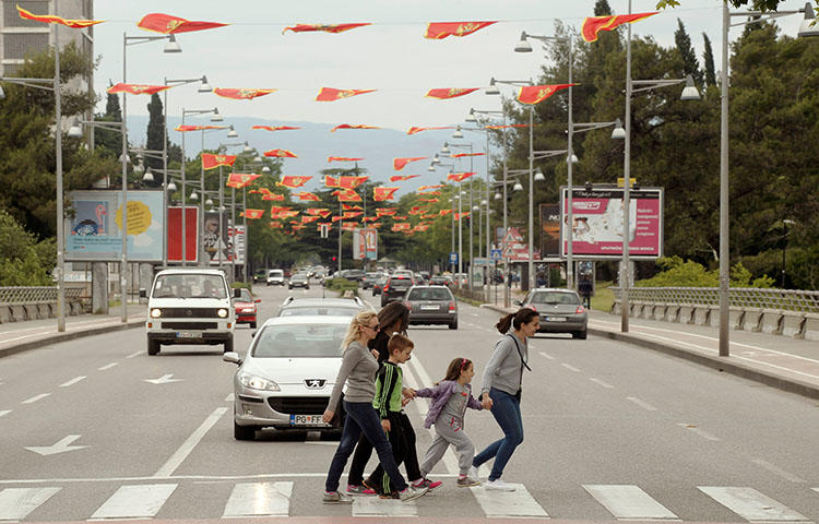 People cross the street decorated with flags in May 2016 as part of the celebrations for Montenegro's Independence Day. A car bomb exploded outside a journalist's home in Montenegro's northern town of Bijelo Polje on April 1, 2018, according to news reports. (Reuters/Stevo Vasiljevic)