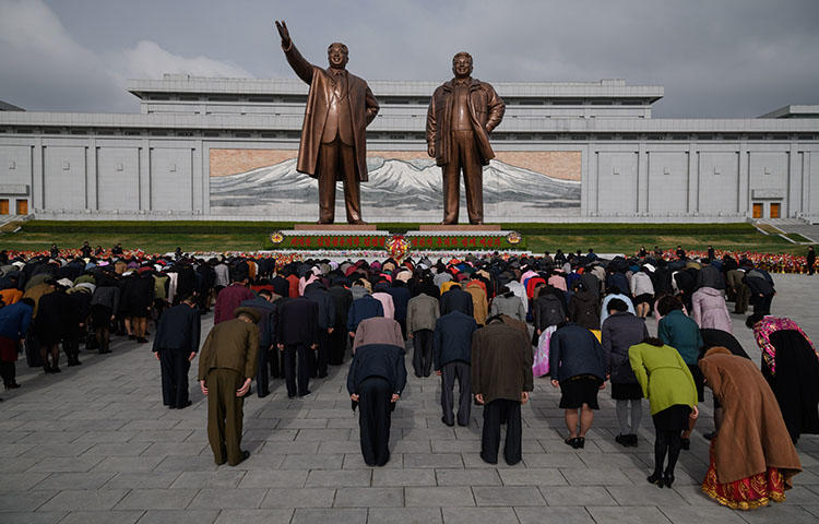 People bow as they pay their respects before the statues of late North Korean leaders Kim Il Sung and Kim Jong Il at Mansu Hill in Pyongyang on April 15, 2018. Eight South Korean journalists were denied entry visas into North Korea to cover the dismantling of a nuclear test site in North Korea, according to news reports. (AFP/Ed Jones)
