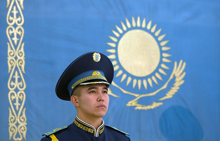 A Kazakh soldier stands in front of the national flag at the presidential palace in Astana, in 2014. CPJ is joining calls for the country to revise its repressive press laws. (AFP/Alain Jocard)