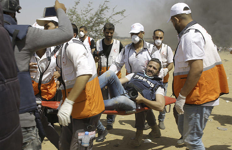 Palestinian medics evacuate a wounded photographer during a protest at the Gaza Strip's border with Israel on May 11, 2018. (AP/Adel Hana)