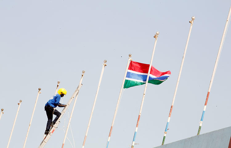 A man fixes Gambia's flag on Feburary 16, 2017, during preparations for the swearing-in ceremony for Gambia's new president, Adama Barrow. Gambia's Supreme Court decided on May 9, 2018, to declare criminal defamation unconstitutional, but upheld segments of the country's criminal code on sedition and false news, according to reports. (Reuters/Thierry Gouegnon)