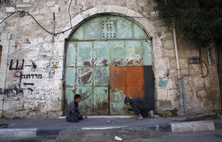 Children play outside a closed store in Hebron in March 2018. Israeli forces arrested a Palestinian photojournalist in the city on June 11. (AFP/Hazem Bader)