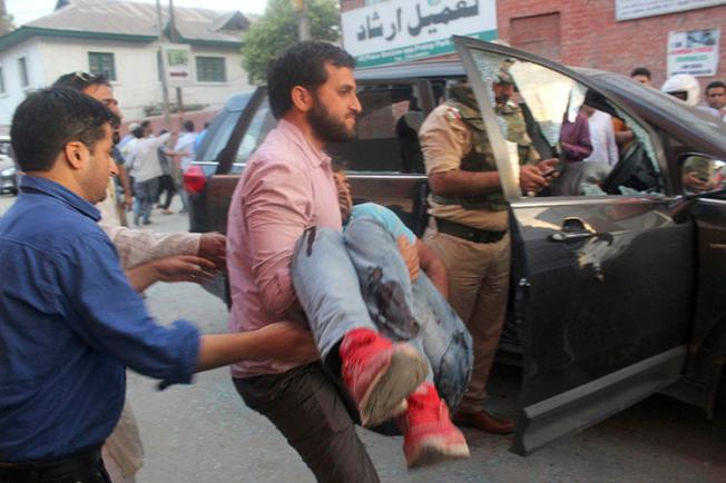 The police bodyguard of journalist Shujaat Bukhari is carried away after an attack in Srinagar, in Indian-controlled Kashmir, on June 14, 2018. Bukhari and two bodyguards were fatally shot as he left his office. (AP Photo)