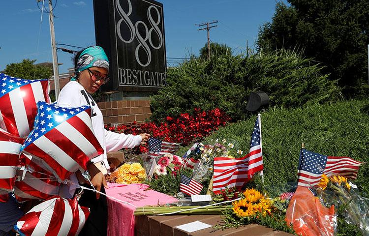 A local resident lays an American flag at an impromptu memorial outside of the Capital Gazette, the day after a gunman killed five people at the newspaper in Annapolis, Maryland, on June 29, 2018. (Reuters/Leah Millis)