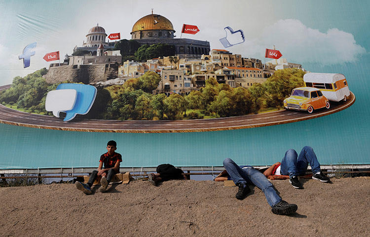 Palestinians rest near an Israeli checkpoint near Ramallah in the West Bank on June 1, 2018. Palestinian authorities to detained Abdul Mohsen Shalaldeh, a reporter for the Hamas-affiliated news website Quds News Network, on June 3, according to reports. (Reuters/Mohamad Torokman)