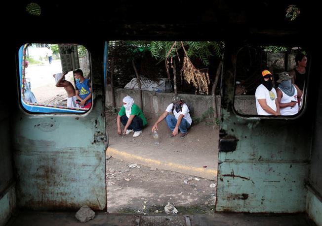 Protesters stand behind a burned bus during an anti-government rally in Tipitapa, Nicaragua on June 14. A Nicaraguan reporter who is covering the unrest says armed attackers broke into his home, beat him, and stole his identification documents. (Reuters/Oswaldo Rivas)