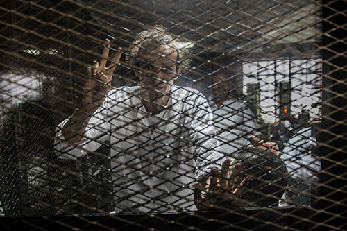 Mahmoud Abou Zeid, known as Shawkan, gestures from inside a soundproof glass dock in August 2016. Shawkan has been in detention since 2013. A verdict in his case is expected this month. (AFP/Khaled Desouki)