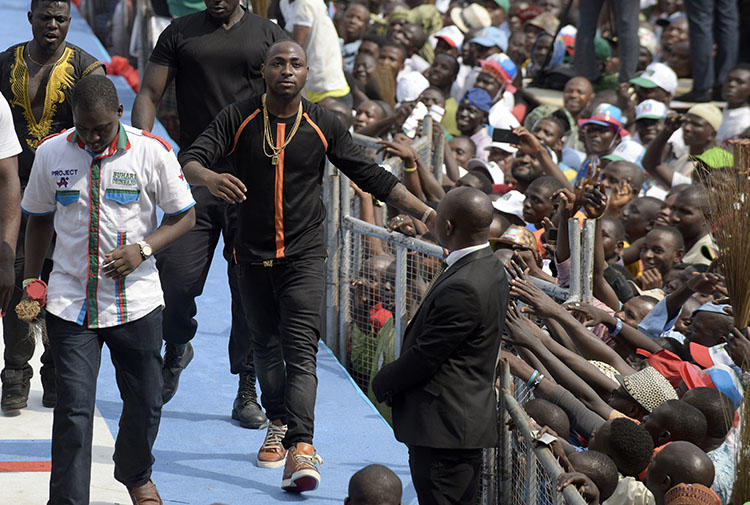 Singer and producer David Adeleke, known as Davido (center) leaves the stage after performing during a political rally in Lagos, Nigeria on January 30, 2015. A member of Davido's private security team assaulted Adekanmbi Damilola, CEO of the online entertainment news platform NoStoryTV, during a concert on July 21, 2018, according to reports. (AFP/Pius Utomi Ekpei)