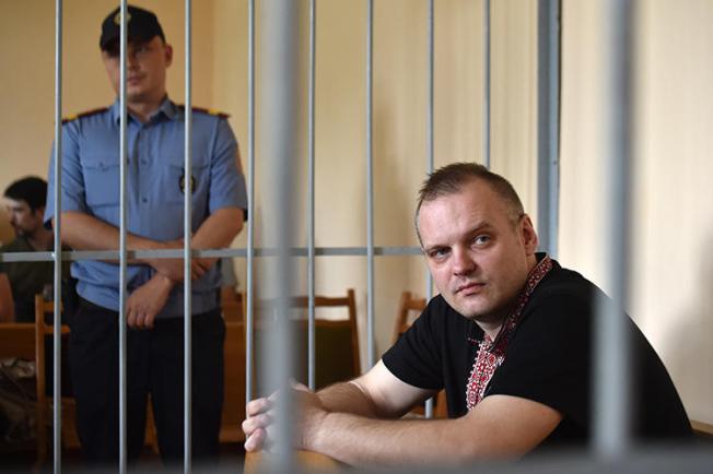 Independent journalist Dzmitry Halko sits in the defendants' cage during his trial in Minsk on July 17, 2018. The court sentenced Halko to four years' detention at a prison colony. (AFP/Sergei Gapon)
