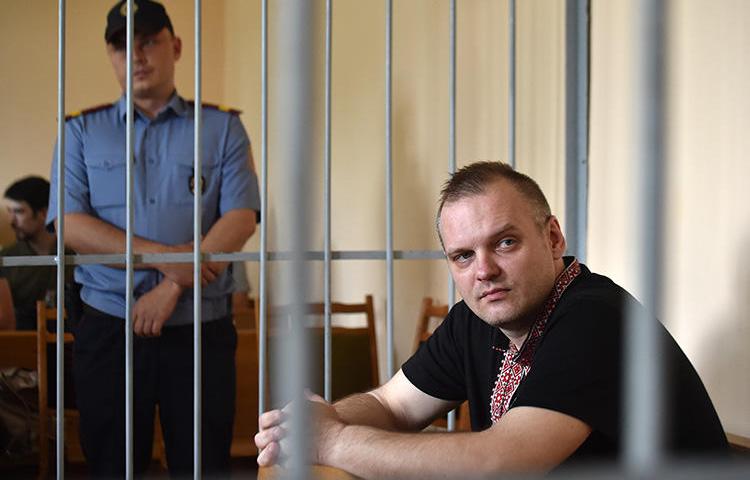 Independent journalist Dzmitry Halko sits in the defendants' cage during his trial in Minsk on July 17, 2018. The court sentenced Halko to four years' detention at a prison colony. (AFP/Sergei Gapon)