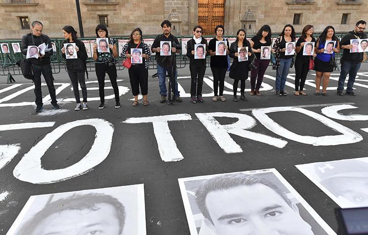 Members of the press hold images of colleagues during a protest against the murder or disappearance of journalists and photojournalists in Mexico, in front of the National Palace in Mexico City on June 1, 2018. Mexican journalist and media owner Rubén Pat was killed in Playa del Carmen, in the southern Mexican state of Quintana Roo, on July 24. (AFP/Yuri Cortez)