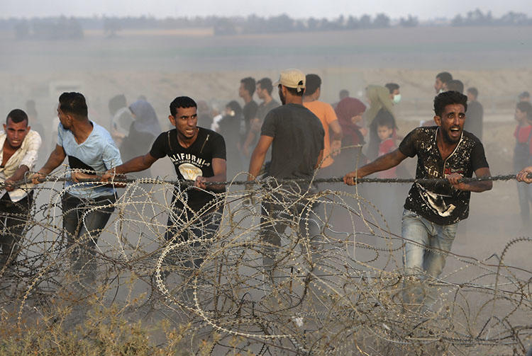Protesters try to move part of the fence along the Gaza Strip border with Israel during a protest east of Khan Younis in the southern Gaza Strip on July 20, 2018. Freelance photojournalist Zaki Yahya Awadallah was hit by a live round fired by the Israel Defense Force while covering a protest east of Rafah city on July 20, according to reports. (AP/Adel Hana)