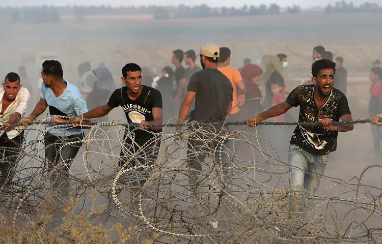 Protesters try to move part of the fence along the Gaza Strip border with Israel during a protest east of Khan Younis in the southern Gaza Strip on July 20, 2018. Freelance photojournalist Zaki Yahya Awadallah was hit by a live round fired by the Israel Defense Force while covering a protest east of Rafah city on July 20, according to reports. (AP/Adel Hana)