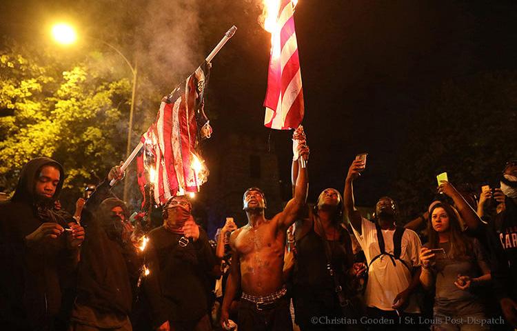 In a photo taken by St. Louis Post-Dispatch photographer Christian Gooden, Black Lives Matter protesters and others burn U.S. flags during a protest in September 2017. Gooden was hit by pepper spray while covering the protests. (Christian Gooden/St. Louis Post-Dispatch)
