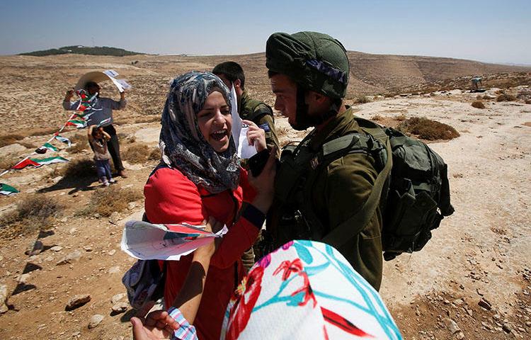 A Palestinian woman argues with an Israeli soldier as the Israeli army removes containers used as a school, near Hebron in the occupied West Bank, on July 11, 2018. Israeli security forces arrested prominent Palestinian writer in Hebron on July 24. (Reuters/Mussa Qawasma)