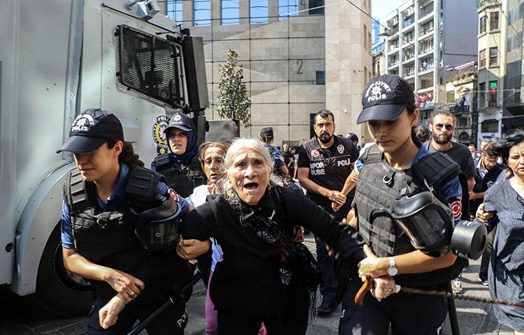 Riot police detain Emine Ocak, a member of Saturday Mothers group, during a demonstration on August 25, 2018, in Istanbul. Turkish police assaulted reporters at the August 25 protest. (AFP/Hayri Tunc)