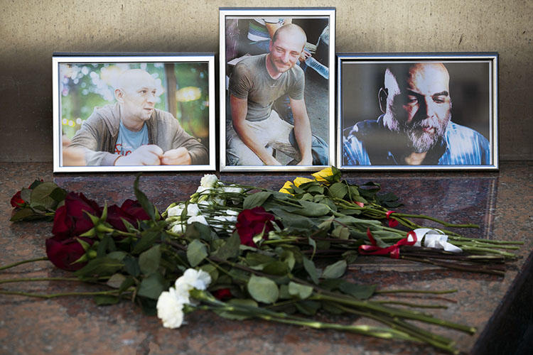 Flowers and photos of Aleksandr Rastorguyev, Kirill Radchenko, and Orkhan Dzhemal are left at the journalist union building in Moscow. The Russian journalists were killed while on assignment in the Central African Republic. (AP/Pavel Golovkin)