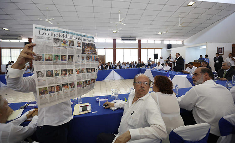 Durante un diálogo nacional con el presidente Daniel Ortega en mayo de 2018, una mujer sostiene un periódico que muestra imágenes de personas que murieron en las protestas en Nicaragua. Más medios de comunicación están ofreciendo noticias contundentes sobre la represión violenta. (AP / Alfredo Zuniga)