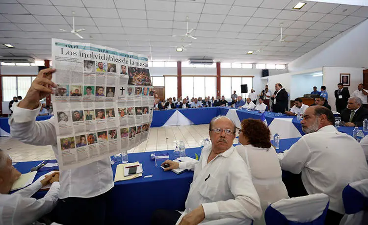 At a national dialogue with President Daniel Ortega in May 2018, a woman holds up a newspaper showing images of people who died in protests in Nicaragua. More media outlets are providing hard-hitting news about the violent crackdown. (AP/Alfredo Zuniga)