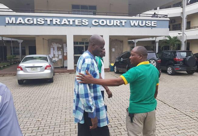 Jones Abiri, left, pictured leaving a court appearance in Abuja on August 2, 2018. The journalist has been detained for two years. (Ahmad Salkida)