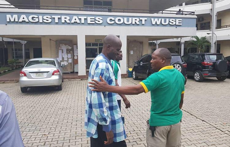 Jones Abiri, left, pictured leaving a court appearance in Abuja on August 2, 2018. The journalist has been detained for two years. (Ahmad Salkida)