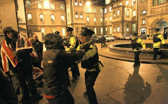 Police Service of Northern Ireland officers confront U.K. loyalists as they try to force their way into Belfast City Hall in 2012. Police arrested two journalists in relation to allegedly stolen confidential documents about a 1994 massacre. (AP/Peter Morrison)