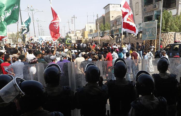 Iraqis shout slogans as security forces form a human barrier during ongoing protests in the southern city of Basra on August 5, 2018. Between July 14 and September 6, 2018, at least seven Iraqi journalists were assaulted or detained while covering protests, and the offices of two local media outlets were set on fire. (AFP/Haidar Mohammed Ali)