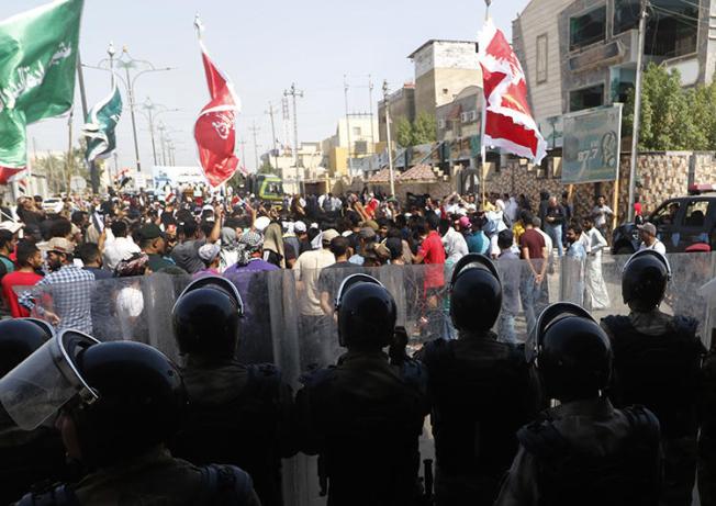 Iraqis shout slogans as security forces form a human barrier during ongoing protests in the southern city of Basra on August 5, 2018. Between July 14 and September 6, 2018, at least seven Iraqi journalists were assaulted or detained while covering protests, and the offices of two local media outlets were set on fire. (AFP/Haidar Mohammed Ali)