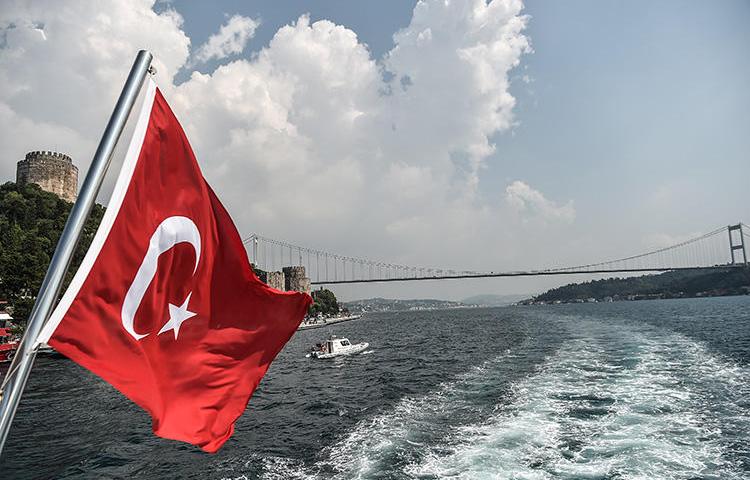 A Turkish flag waves over the Bosphorus strait as Fatih Sultan Mehmet Bridge is seen in the background, on July 22, 2018, in Istanbul. (AFP/Ozan Kose)