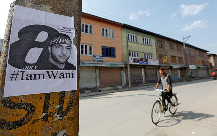 A man rides his bicycle in Srinagar past a poster of Burhan Wani, a commander of the Hizbul Mujahideen militant group who was killed in 2016. Kashmiri authorities arrested and questioned a journalist after he wrote a cover story on the commander. (Reuters/Danish Ismail)